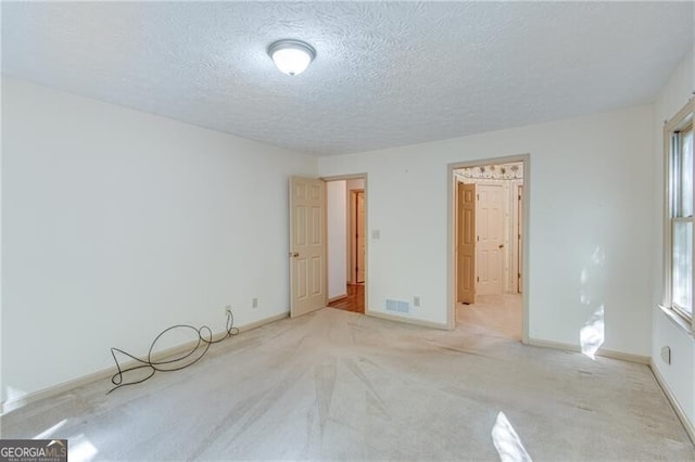 empty room with a textured ceiling and light colored carpet