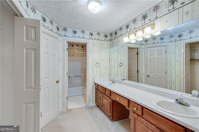 full bath with wallpapered walls, double vanity, a textured ceiling, and toilet