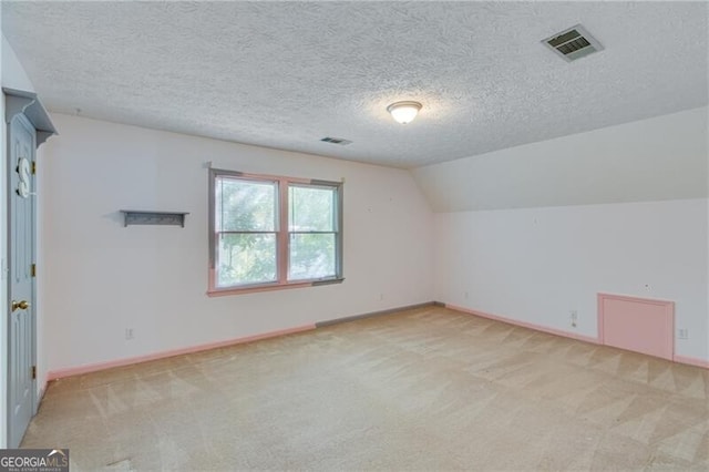 bonus room with a textured ceiling, light colored carpet, and vaulted ceiling