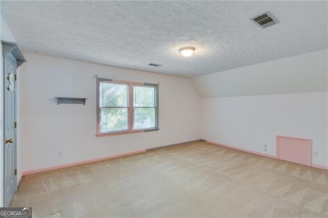 additional living space with light carpet, baseboards, a textured ceiling, and lofted ceiling