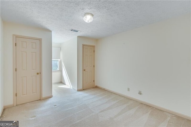 unfurnished room featuring light colored carpet, baseboards, and a textured ceiling