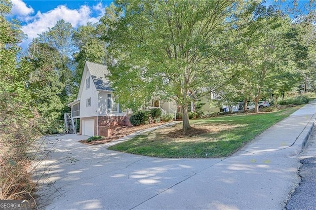 view of home's exterior featuring a garage, concrete driveway, brick siding, and stairway
