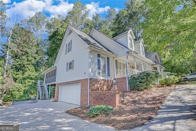 view of property exterior featuring stairs, covered porch, brick siding, an attached garage, and concrete driveway