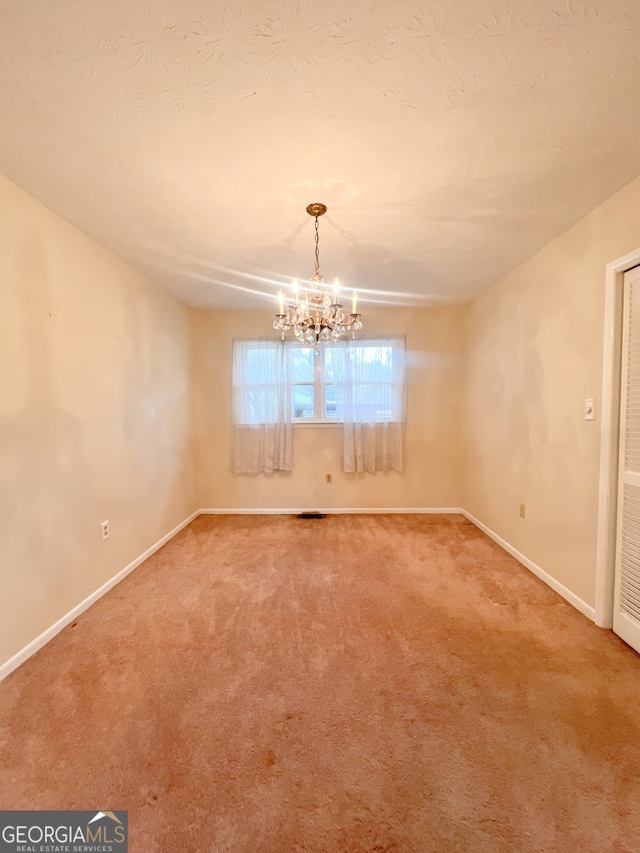 spare room with carpet flooring and an inviting chandelier