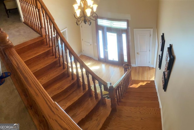 stairs with wood-type flooring and a chandelier