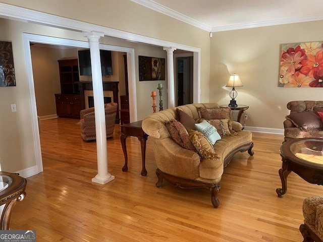 living room with light hardwood / wood-style floors, crown molding, and decorative columns