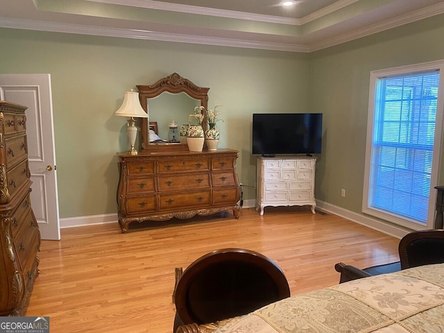 bedroom with crown molding, a raised ceiling, and light wood-type flooring