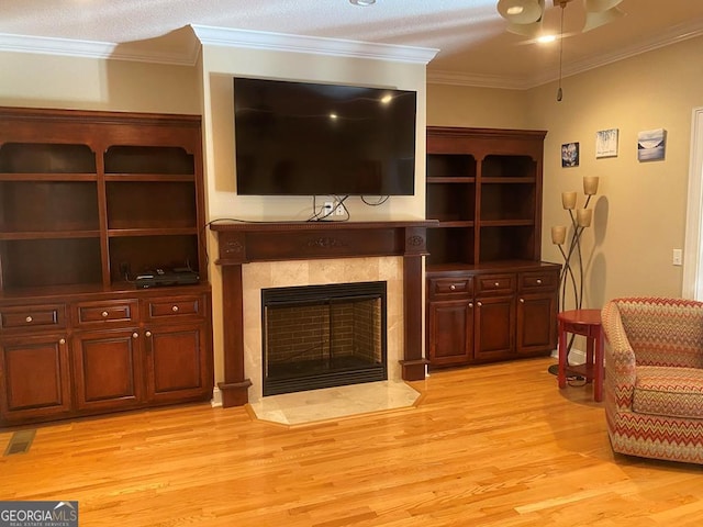 living room featuring light hardwood / wood-style flooring, a textured ceiling, a fireplace, and crown molding