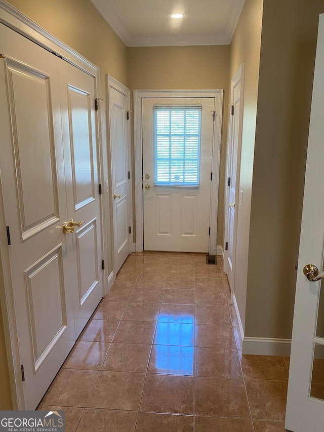 doorway with ornamental molding and light tile patterned floors