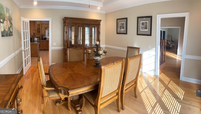 dining room featuring crown molding, light hardwood / wood-style flooring, and french doors