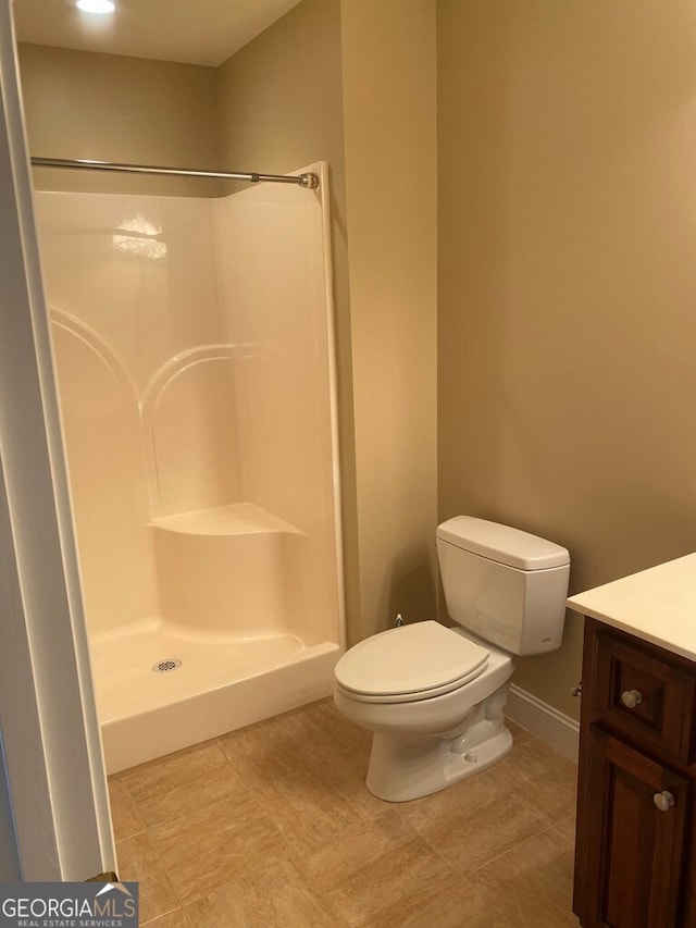 bathroom featuring toilet, walk in shower, and vanity