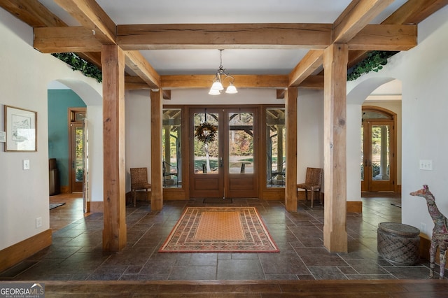 foyer entrance featuring a wealth of natural light, beam ceiling, a notable chandelier, and french doors