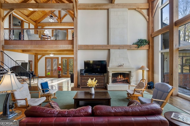 living room featuring beam ceiling, wood-type flooring, a fireplace, and high vaulted ceiling