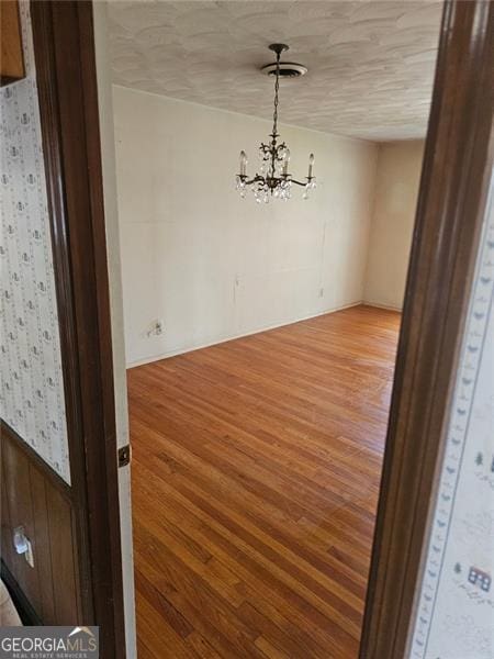 spare room featuring a notable chandelier and wood-type flooring