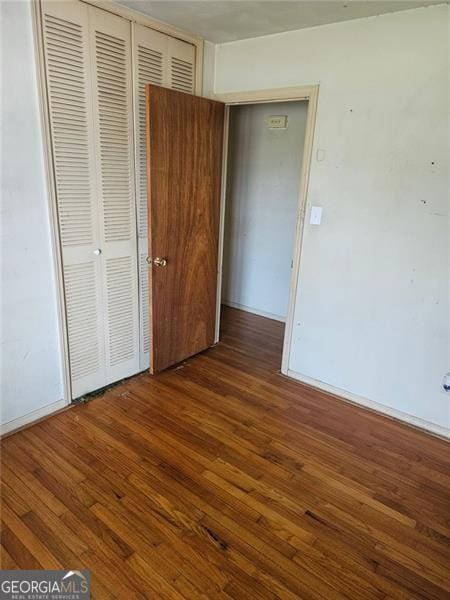 unfurnished bedroom with a closet and dark hardwood / wood-style floors