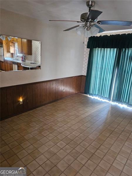 tiled spare room with ceiling fan, wood walls, and sink