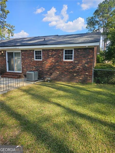 back of property with a lawn and cooling unit