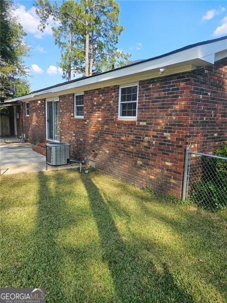 rear view of house featuring a patio, central air condition unit, and a lawn