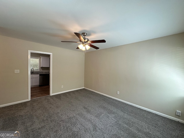 unfurnished bedroom with dark colored carpet, ensuite bath, and ceiling fan