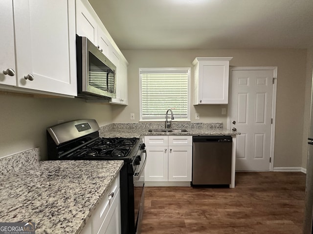 kitchen with dark wood-type flooring, sink, white cabinetry, appliances with stainless steel finishes, and light stone counters