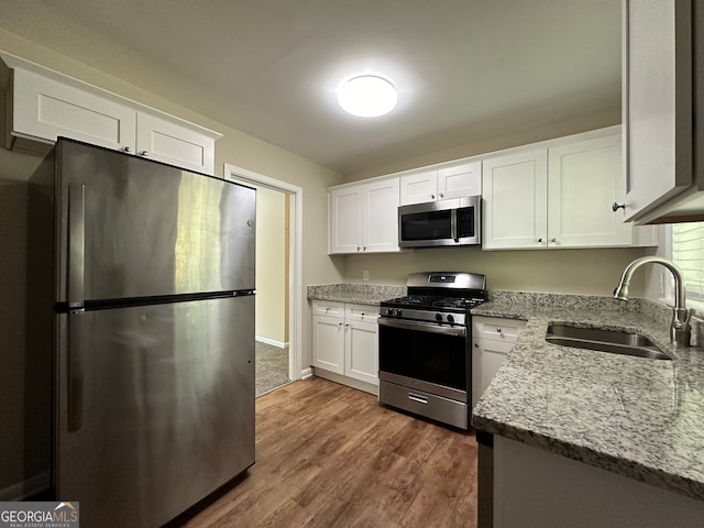 kitchen featuring dark hardwood / wood-style floors, stainless steel appliances, sink, white cabinetry, and light stone counters