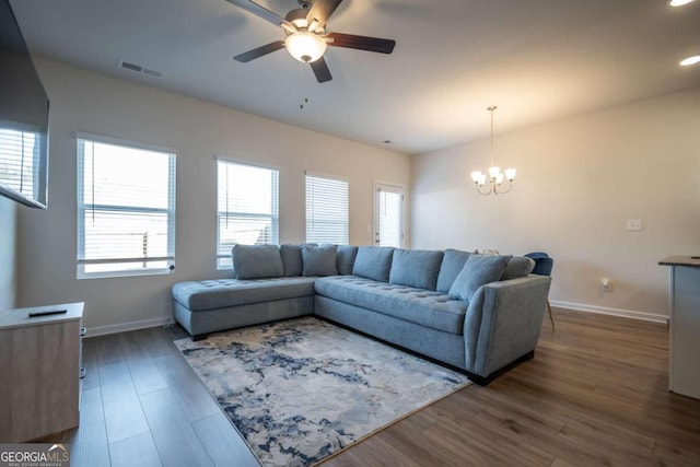 living room with dark hardwood / wood-style floors and ceiling fan with notable chandelier