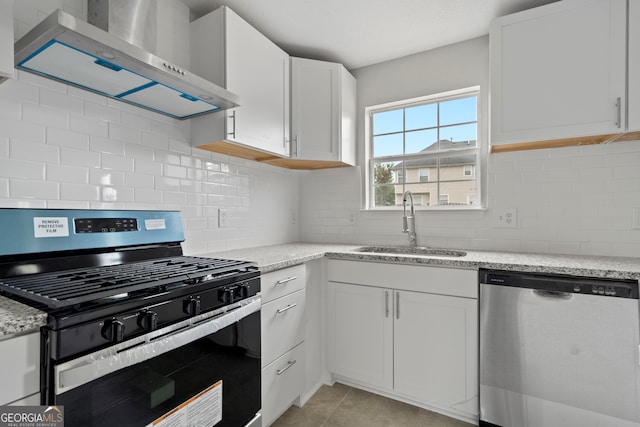 kitchen with black range with gas stovetop, wall chimney exhaust hood, stainless steel dishwasher, and white cabinets