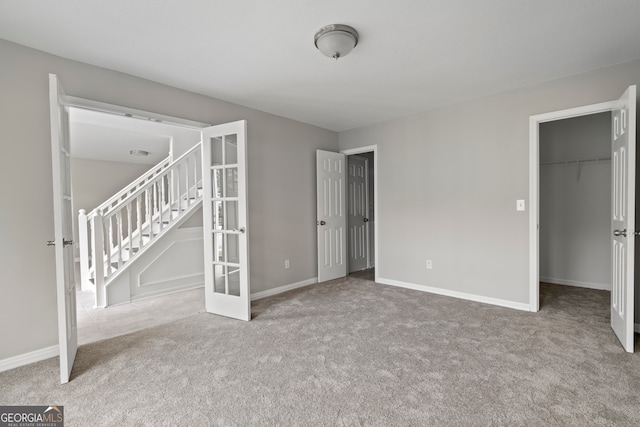 unfurnished bedroom with a spacious closet, a closet, and light colored carpet