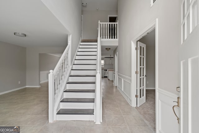 stairs with a towering ceiling and tile patterned floors