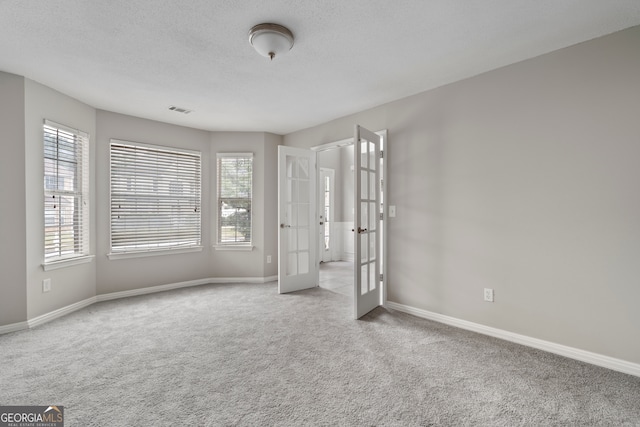 carpeted spare room with french doors and a textured ceiling