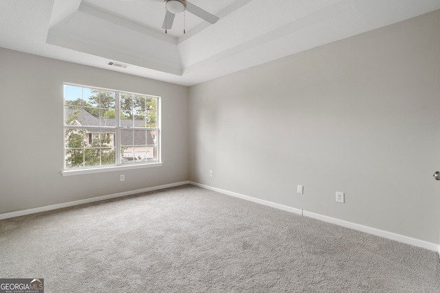 unfurnished room featuring carpet, ceiling fan, and a raised ceiling