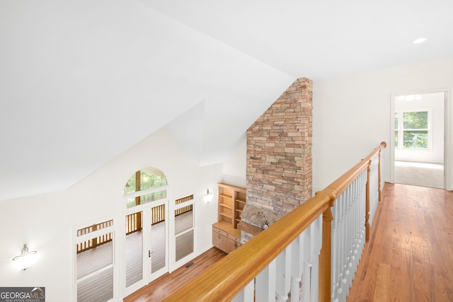 hallway featuring lofted ceiling, light hardwood / wood-style flooring, and a healthy amount of sunlight