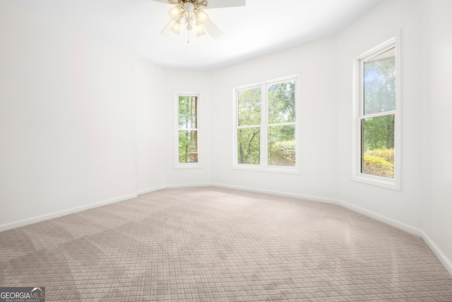 carpeted empty room with ceiling fan and plenty of natural light