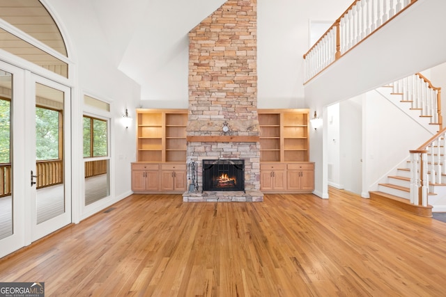 unfurnished living room with high vaulted ceiling, light wood-type flooring, and a fireplace