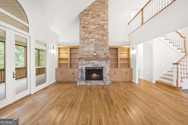 124 S Shore Dr, Fair Play, SC 29643 - unfurnished living room featuring high vaulted ceiling, light wood-style flooring, a stone fireplace, stairway, and baseboards