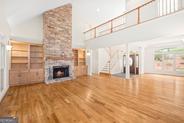 unfurnished living room featuring high vaulted ceiling, light wood-type flooring, and a fireplace