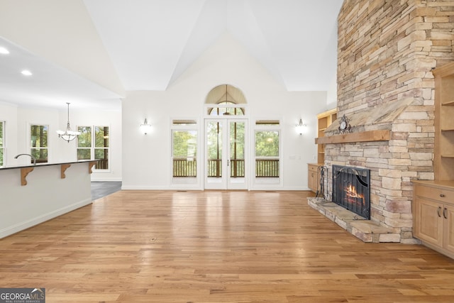 124 S Shore Dr, Fair Play, SC 29643 - unfurnished living room with a stone fireplace, a chandelier, light wood-style flooring, high vaulted ceiling, and baseboards