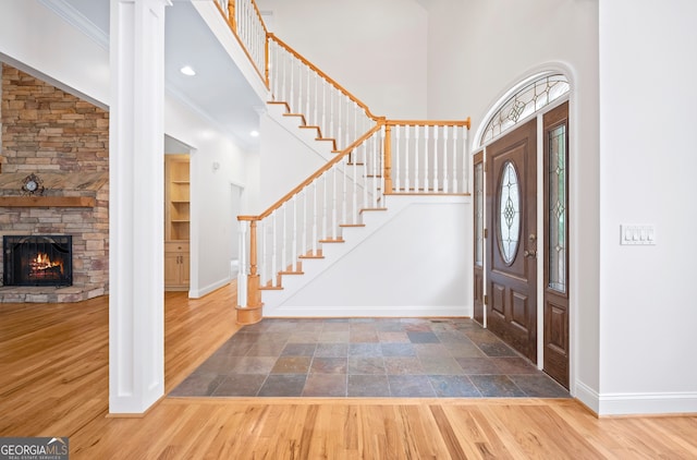 entrance foyer with wood-type flooring, a high ceiling, and ornamental molding