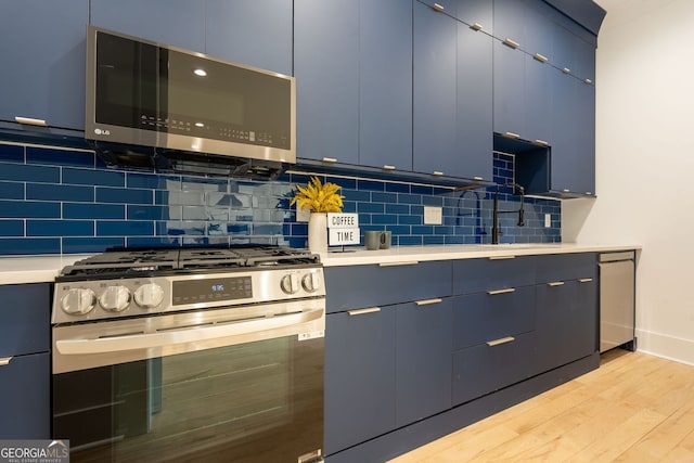 kitchen featuring blue cabinetry, appliances with stainless steel finishes, tasteful backsplash, and light wood-type flooring