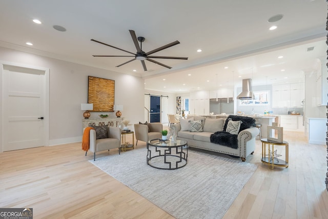 living room featuring crown molding, ceiling fan, sink, and light hardwood / wood-style flooring