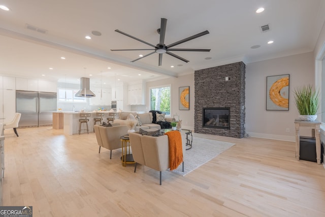 living room with crown molding, ceiling fan, a fireplace, and light hardwood / wood-style flooring