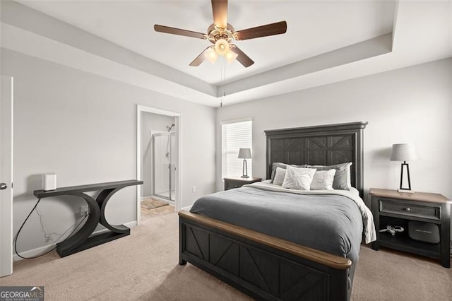 carpeted bedroom with a tray ceiling and ceiling fan