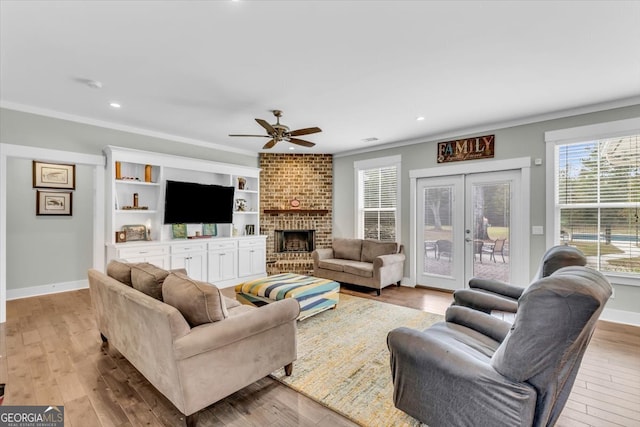 living room featuring ornamental molding, french doors, light hardwood / wood-style flooring, and a brick fireplace