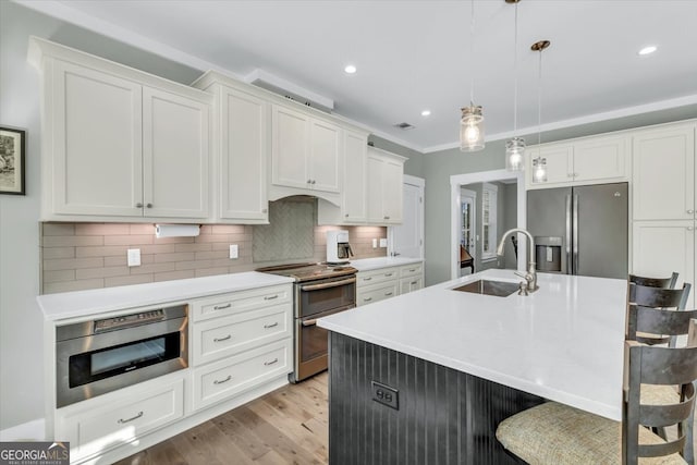 kitchen with decorative backsplash, stainless steel appliances, sink, decorative light fixtures, and white cabinetry