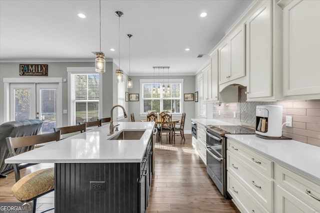 kitchen featuring hanging light fixtures, an island with sink, white cabinetry, stainless steel range with electric stovetop, and sink