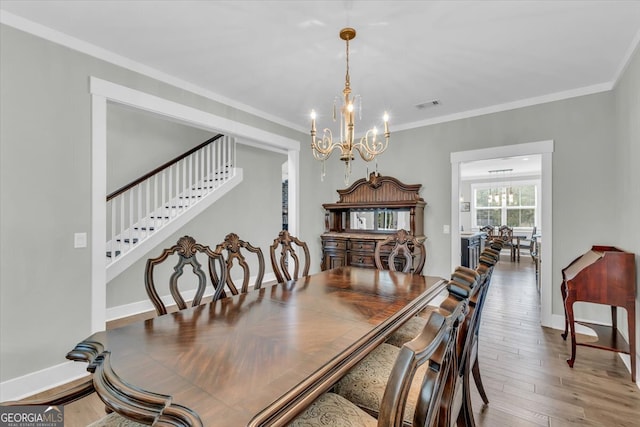 dining area with crown molding, wood-type flooring, and a chandelier