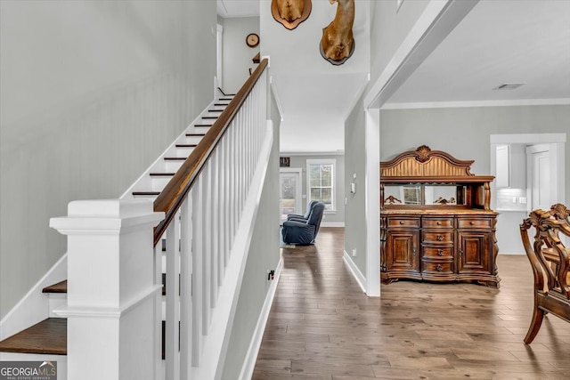 staircase featuring crown molding and wood-type flooring