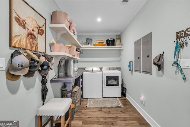 clothes washing area featuring wood-type flooring, electric panel, and separate washer and dryer