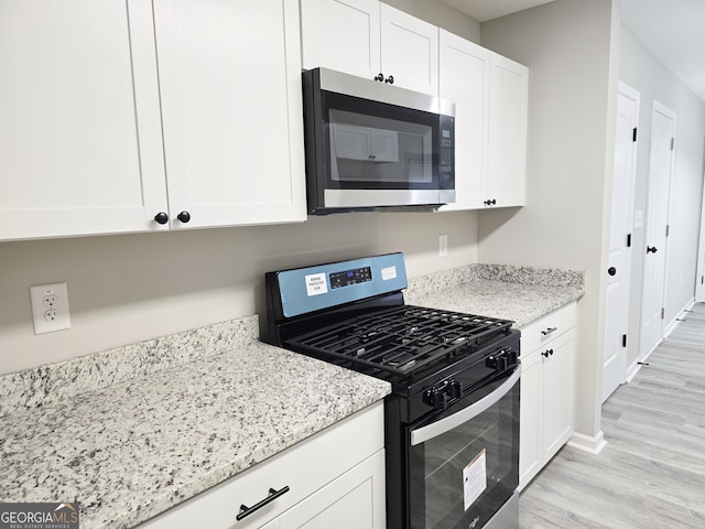 kitchen featuring white cabinetry, light hardwood / wood-style floors, appliances with stainless steel finishes, and light stone countertops