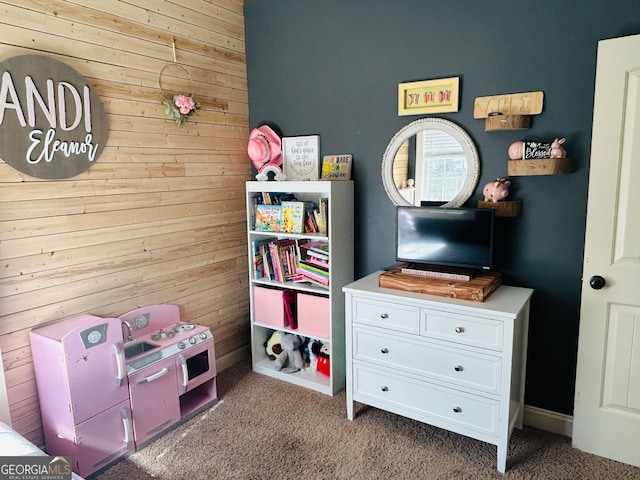 recreation room featuring wood walls and dark carpet